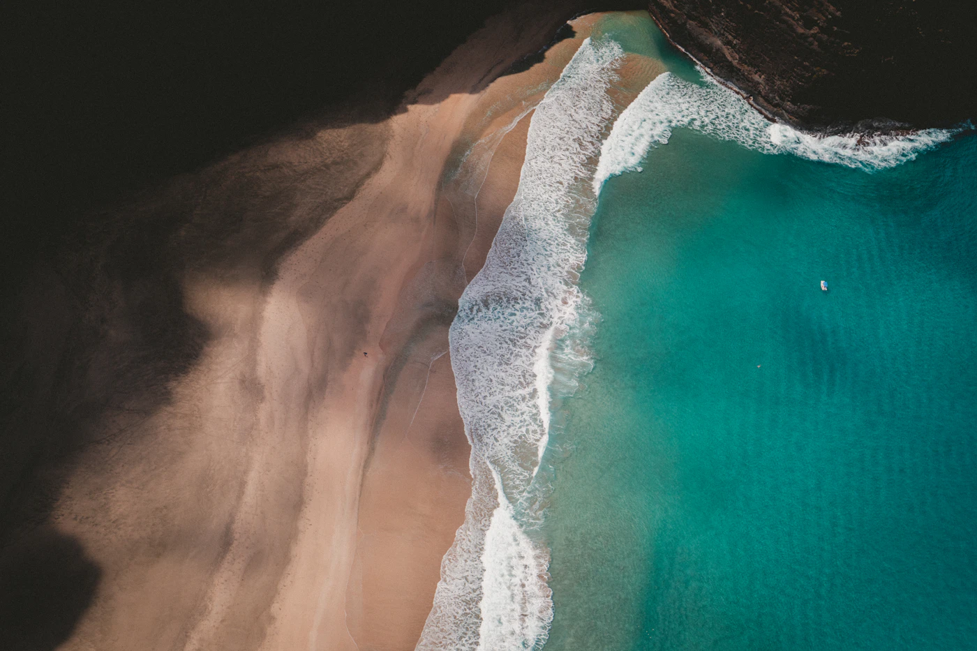 Waves folding onto a sand beach, seen from directly above