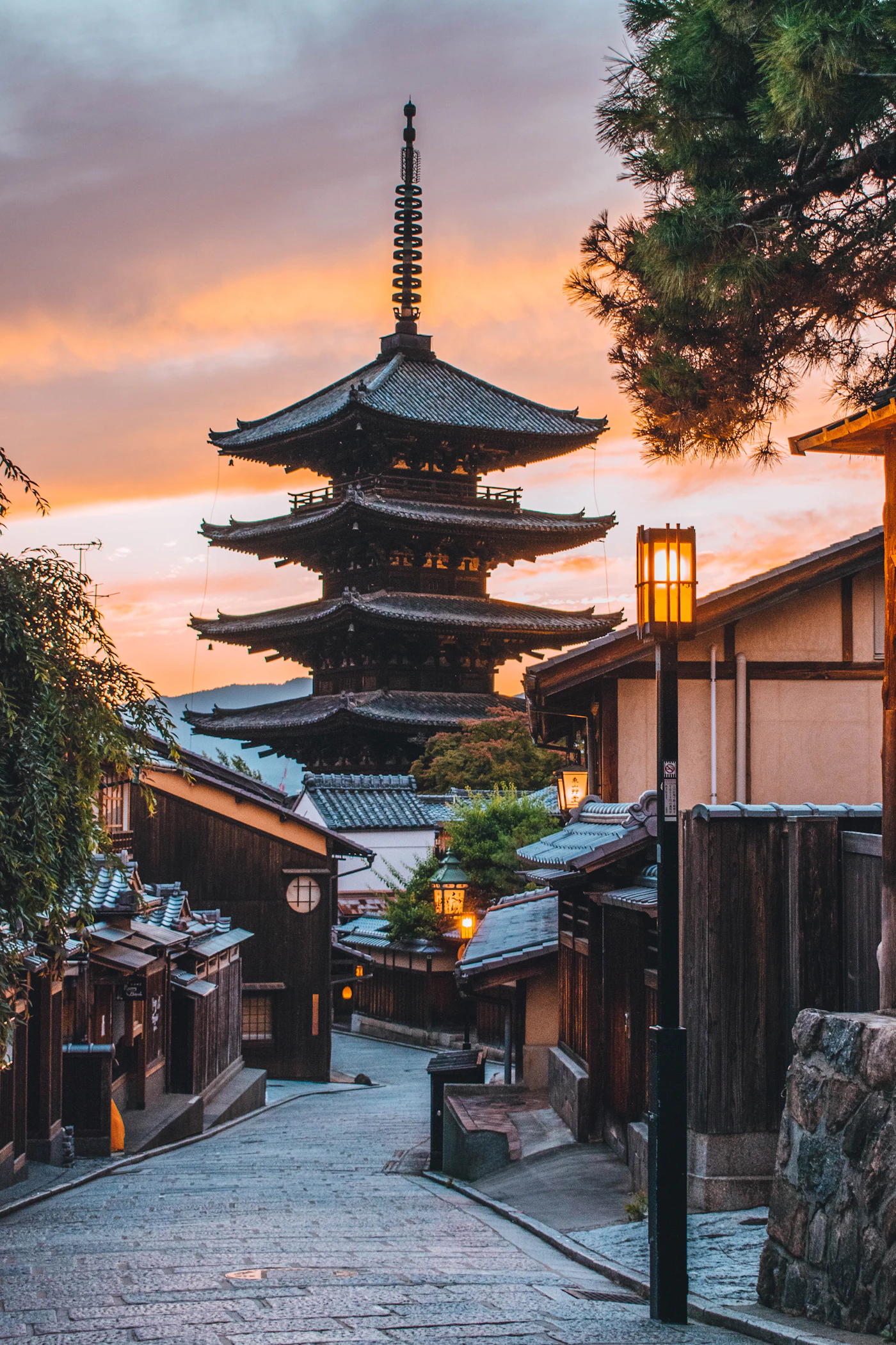 A traditional pagoda above a narrow Kyoto street at golden hour